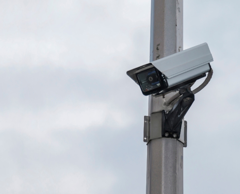 Security camera on a post over cloudy sky background